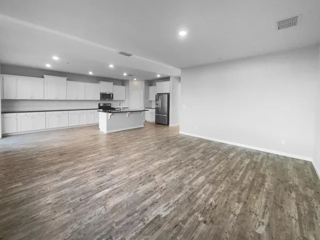 a view of kitchen with kitchen island wooden floor center island and stainless steel appliances