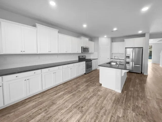 a large kitchen with kitchen island white cabinets and stainless steel appliances