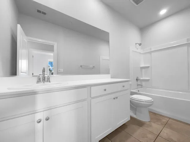 a bathroom with a double vanity sink a toilet and a tub