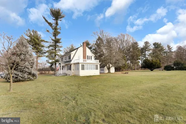 a view of big house with a big yard and large trees