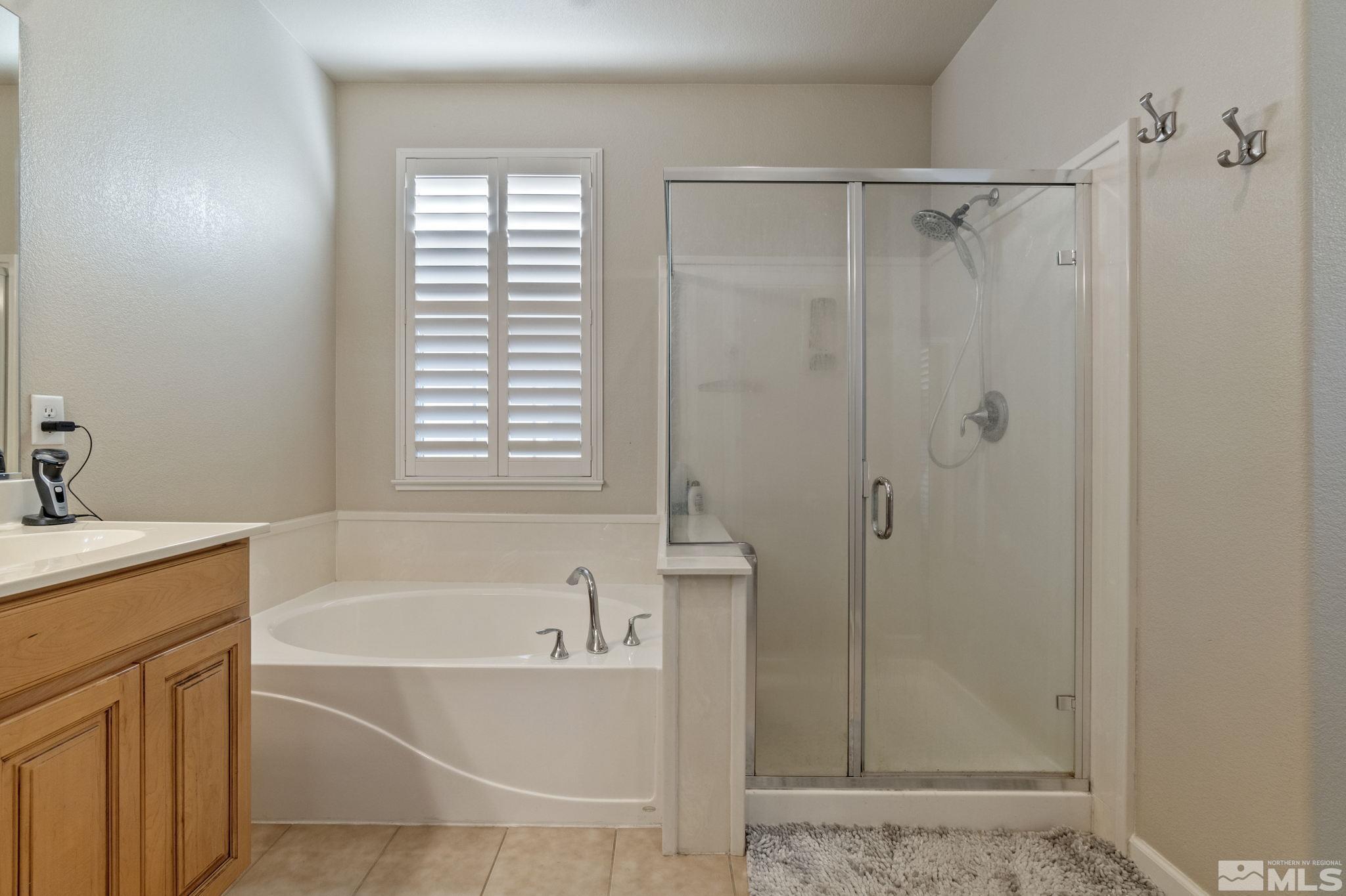 1705 Wind Ranch Road, Unit C Reno, NV 89521 - Photo 23 of 26 a bathroom with a bathtub a shower a sink and a window