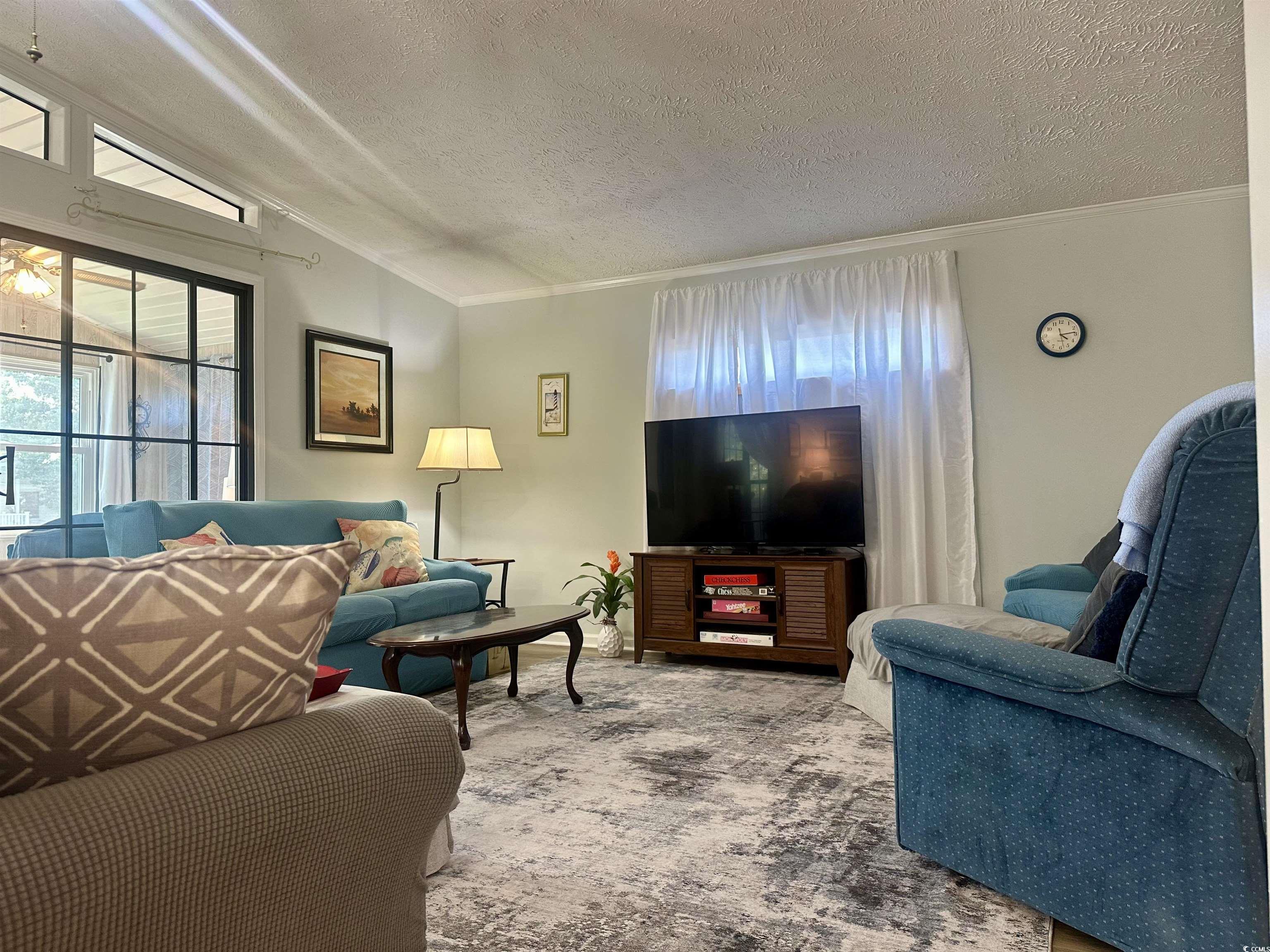 Carpeted living room with crown molding and a text