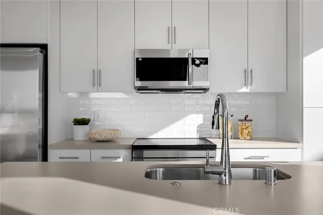 a kitchen with stainless steel appliances a sink a microwave a stove with white cabinets