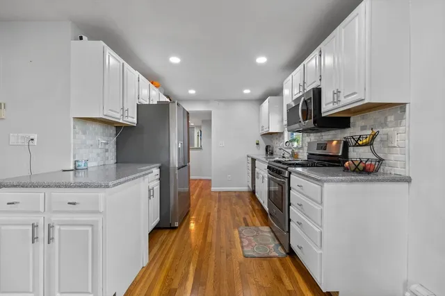 a kitchen with granite countertop a sink a counter top space stainless steel appliances and cabinets