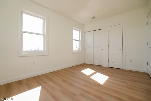 a view of empty room with window and wooden floor
