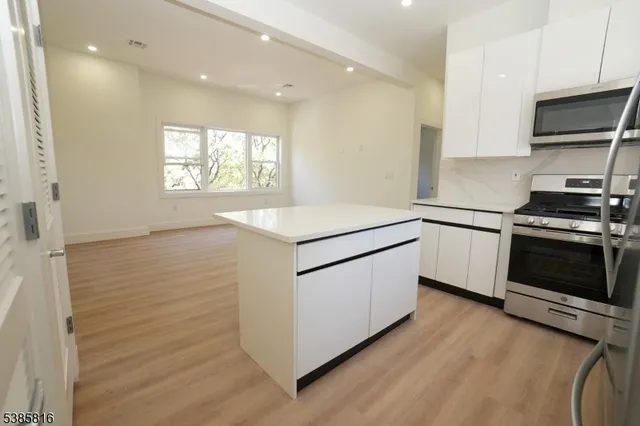 a kitchen with stainless steel appliances white cabinets and wooden floor
