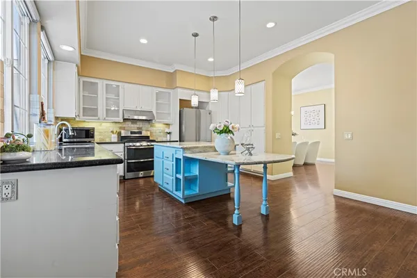 a kitchen with stainless steel appliances kitchen island wooden cabinets and white stove top oven