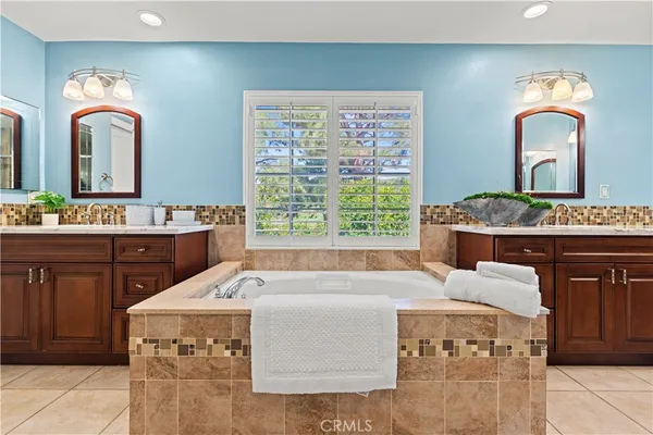 a spacious bathroom with a double vanity sink a mirror and a