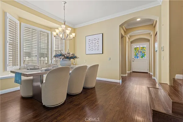 a dining room with wooden floor a chandelier a glass table and windows
