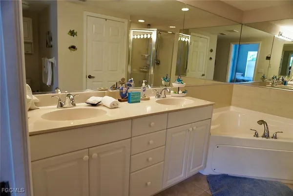 a bathroom with a double vanity sink mirror and bathtub