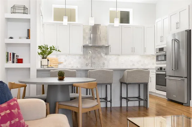 a kitchen with stainless steel appliances kitchen island granite countertop a table chairs and a refrigerator