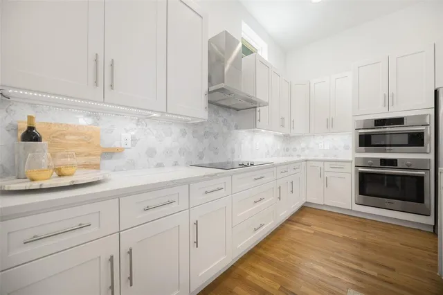 a kitchen with granite countertop white cabinets and stainless steel appliances