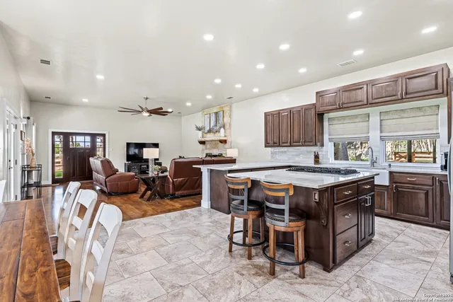 a kitchen with stainless steel appliances granite countertop a table chairs sink and wooden cabinets