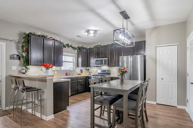 a kitchen with a dining table chairs stainless steel appliances and cabinets