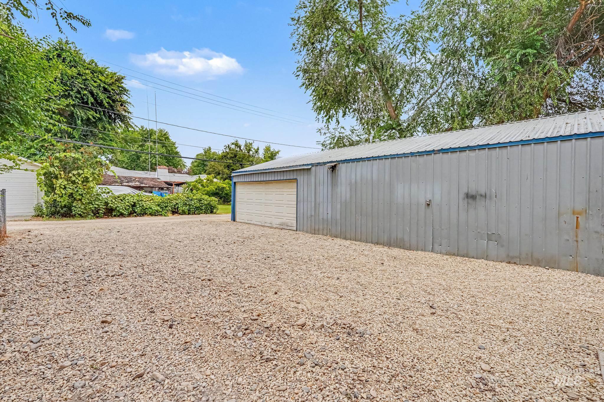 1023 State Street Weiser, ID 83672 - Photo 19 of 25 Expansive gravel yard with a large metal-sided outbuilding featuring a roll-up garage door