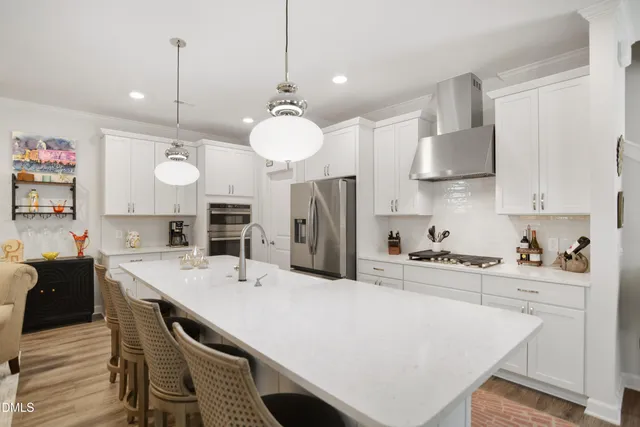 a large kitchen with stainless steel appliances kitchen island a table chairs and a refrigerator