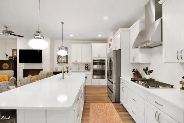 a large kitchen with stainless steel appliances kitchen island granite countertop a stove a sink a oven and a wooden cabinets