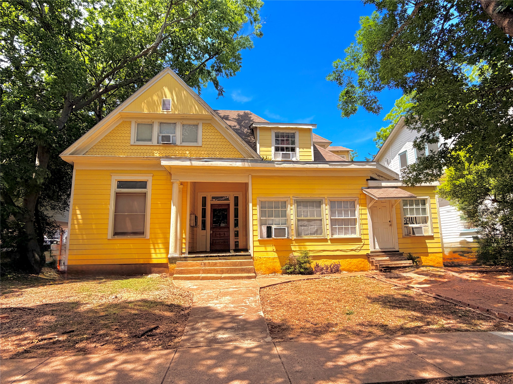 908 West 22nd Street, Unit D Austin, TX 78705 - Photo 1 of 2 Yellow exterior featuring a covered front porch, an intricate wooden entry door, and multiple window styles