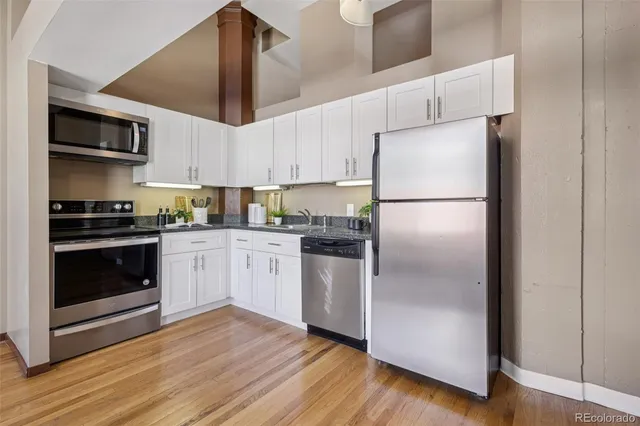 a kitchen with stainless steel appliances granite countertop white cabinets a stove a sink and dishwasher