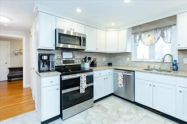 a kitchen with stainless steel appliances granite countertop a stove a sink and a microwave
