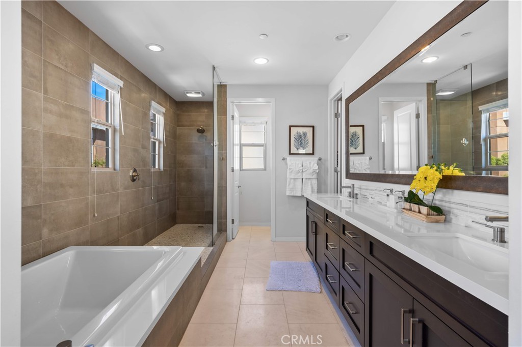 105 Newall Irvine, CA 92618 - Photo 47 of 59 a bathroom with a double vanity sink a large mirror a shower and bathtub