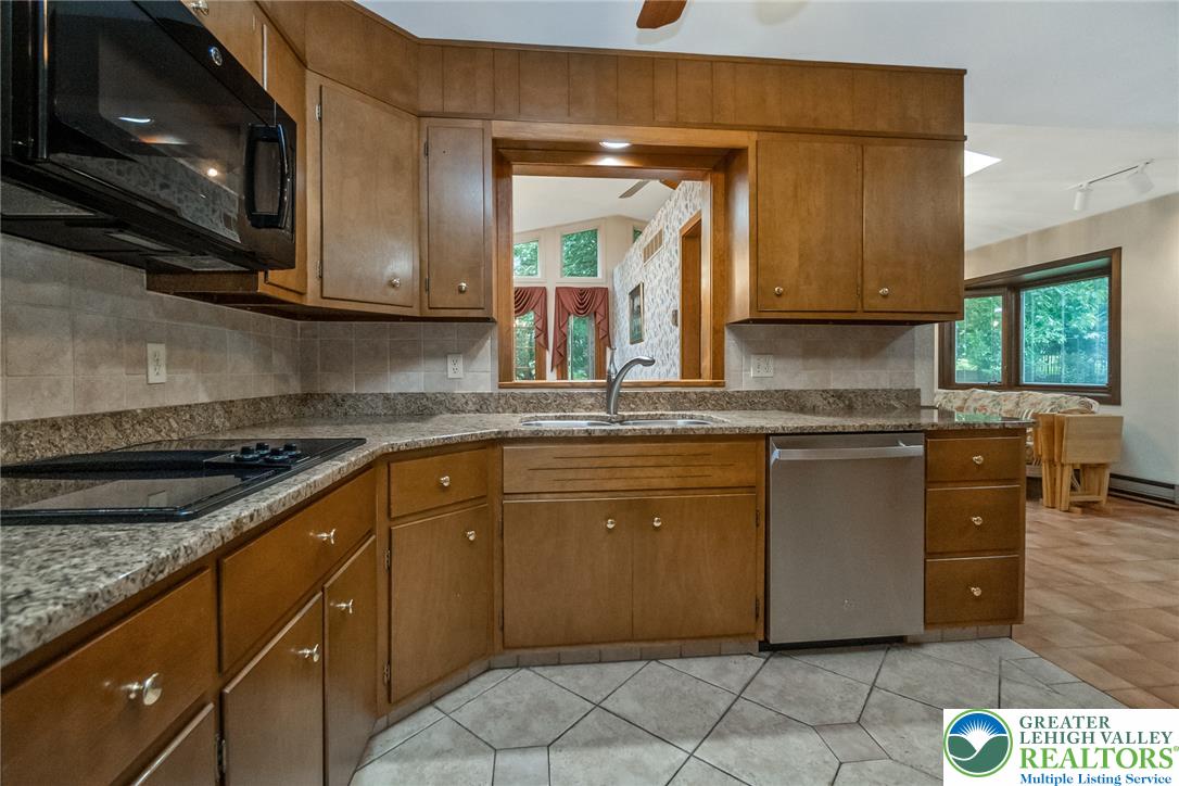 1328 Russett Road Allentown, PA 18104 - Photo 13 of 46 Prepare meals in a kitchen featuring granite countertops and wood cabinetry, complete with essential appliances.
