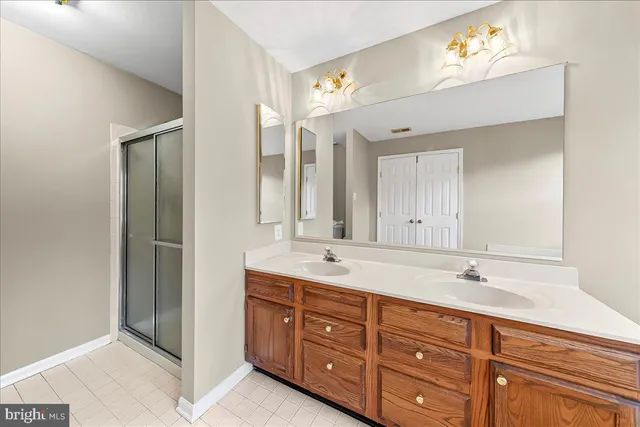 a spacious bathroom with double vanity sinks a vanity a lamp and a mirror
