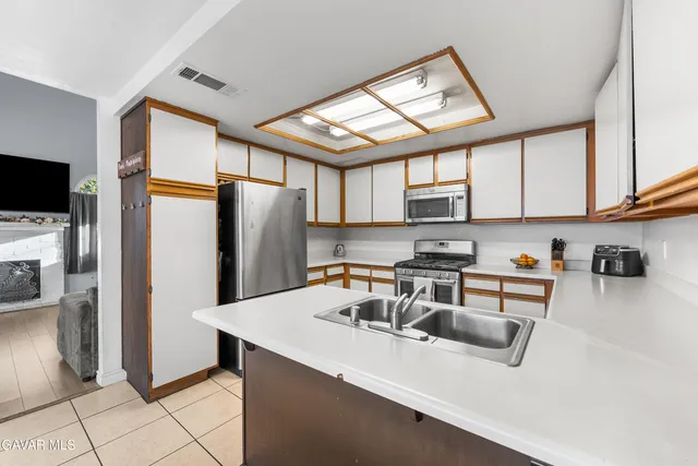 a kitchen with stainless steel appliances granite countertop a refrigerator a sink a stove top oven and a refrigerator