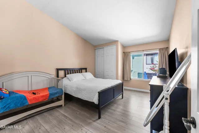 a bedroom with a bed and a flat tv screen on the dresser