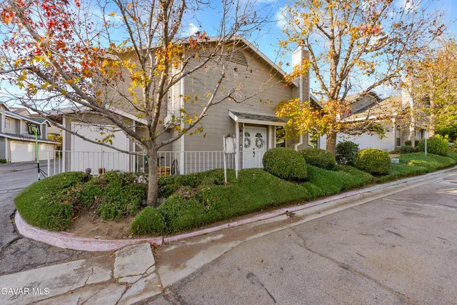 a view of a house with a small yard plants and a large tree