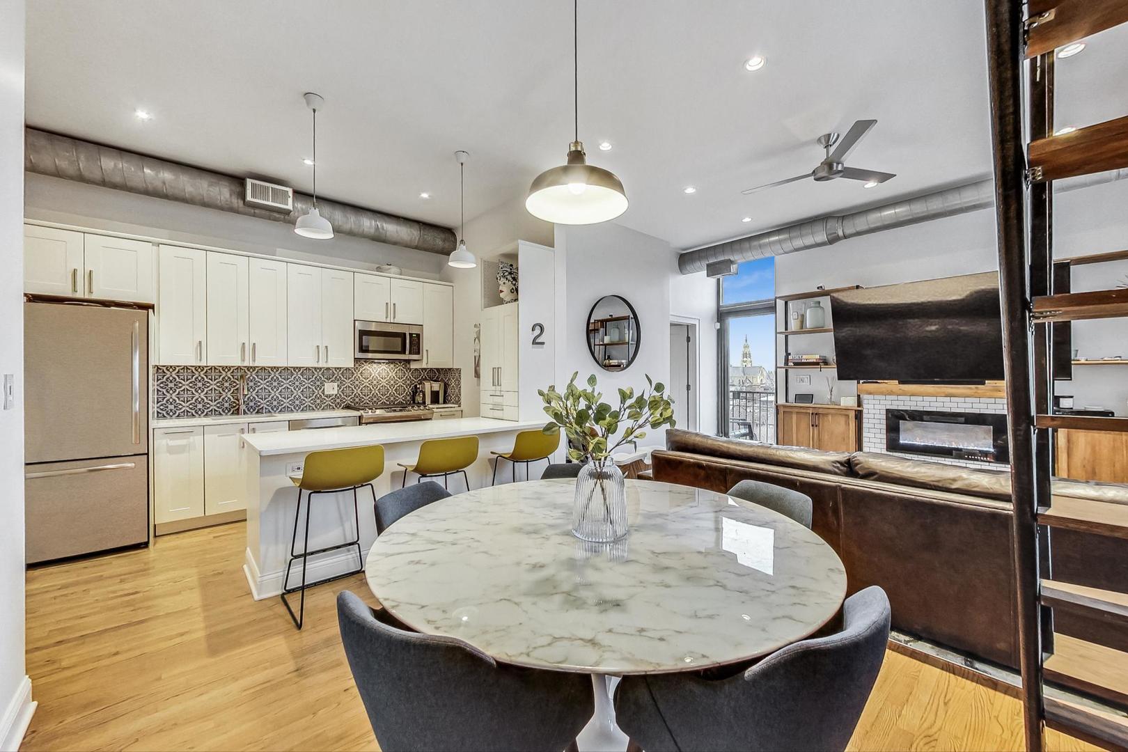 811 South Lytle Street, Unit 611 Chicago, IL 60607 - Photo 6 of 29 a kitchen with stainless steel appliances kitchen island granite countertop a sink a stove and chairs with wooden floor