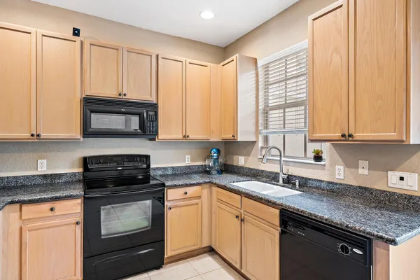 a kitchen with stainless steel appliances granite countertop white cabinets sink and a granite counter top
