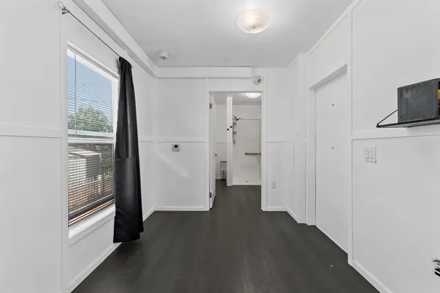 a view of a hallway with wooden floor and a cabinet
