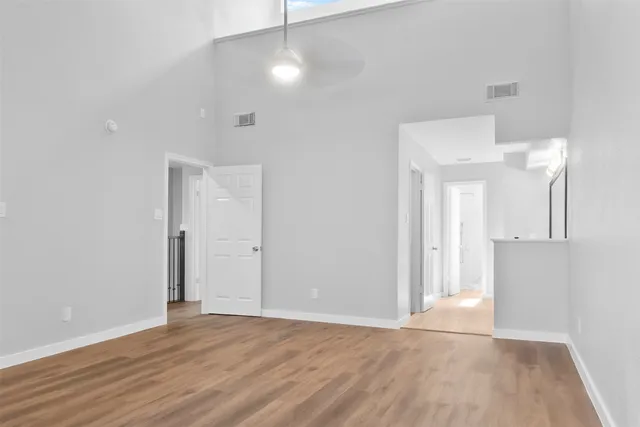 a view of an empty room with wooden floor and a ceiling fan