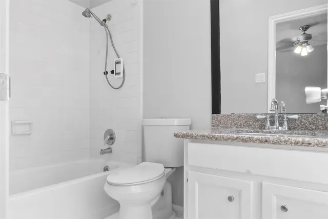 a bathroom with a granite countertop sink a toilet and a bathtub