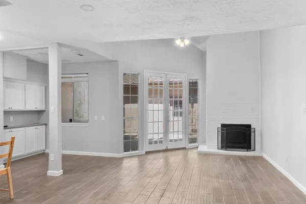 a view of empty room with wooden floor and kitchen