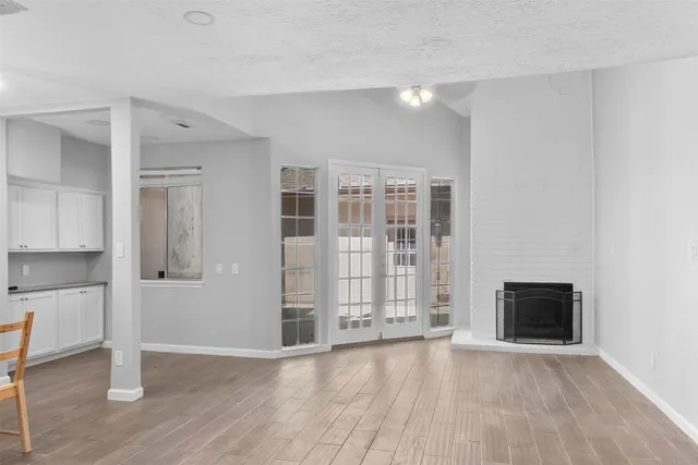 a view of empty room with wooden floor and kitchen