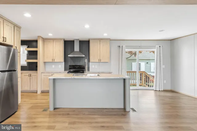 a kitchen with stainless steel appliances granite countertop a refrigerator a stove top oven and a refrigerator with wooden floor