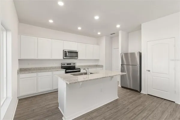 a kitchen with stainless steel appliances granite countertop a refrigerator stove top oven and sink