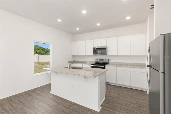 a kitchen with a refrigerator a sink dishwasher a stove and white cabinets with wooden floor