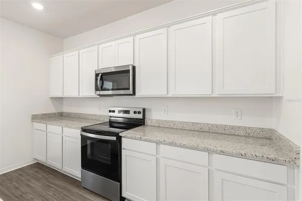 a kitchen with granite countertop white cabinets and white appliances