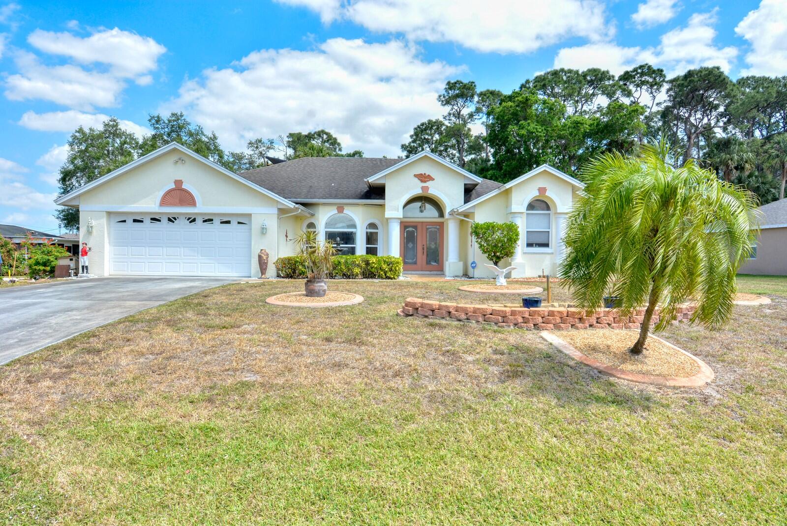 2041 Southwest Villanova Road Port St. Lucie, FL 34953 - Photo 1 of 42 a front view of a house with a yard and trees