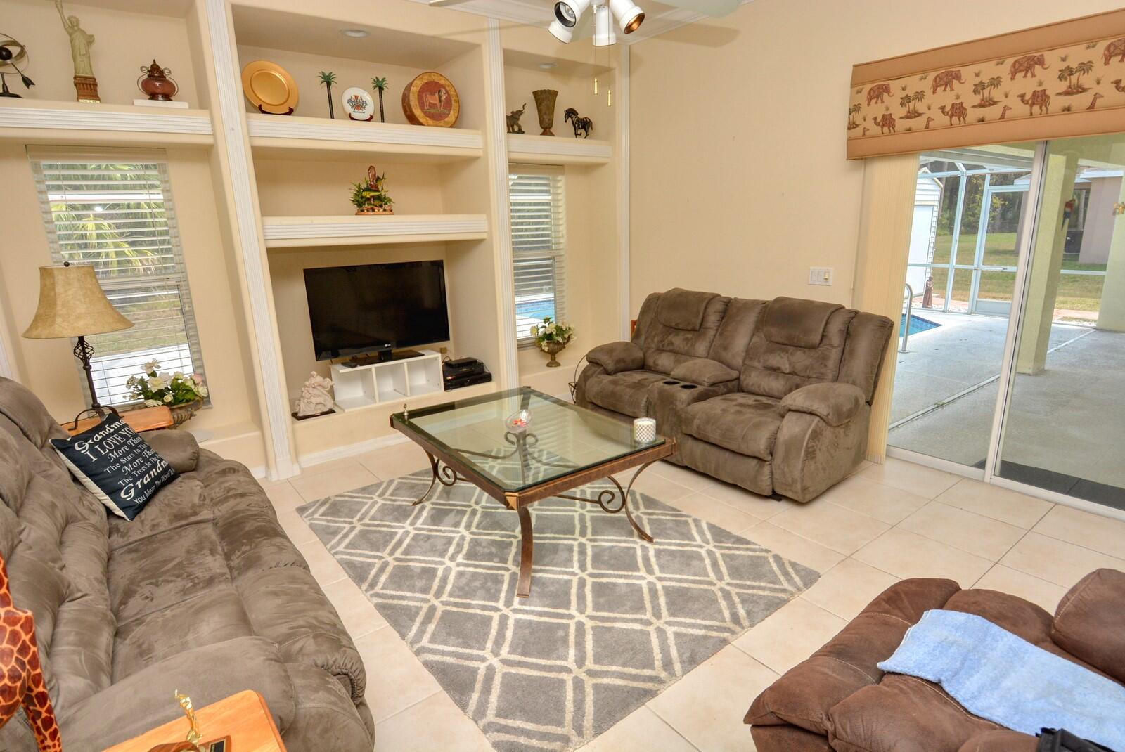 2041 Southwest Villanova Road Port St. Lucie, FL 34953 - Photo 13 of 42 a living room with furniture a flat screen tv and a floor to ceiling window