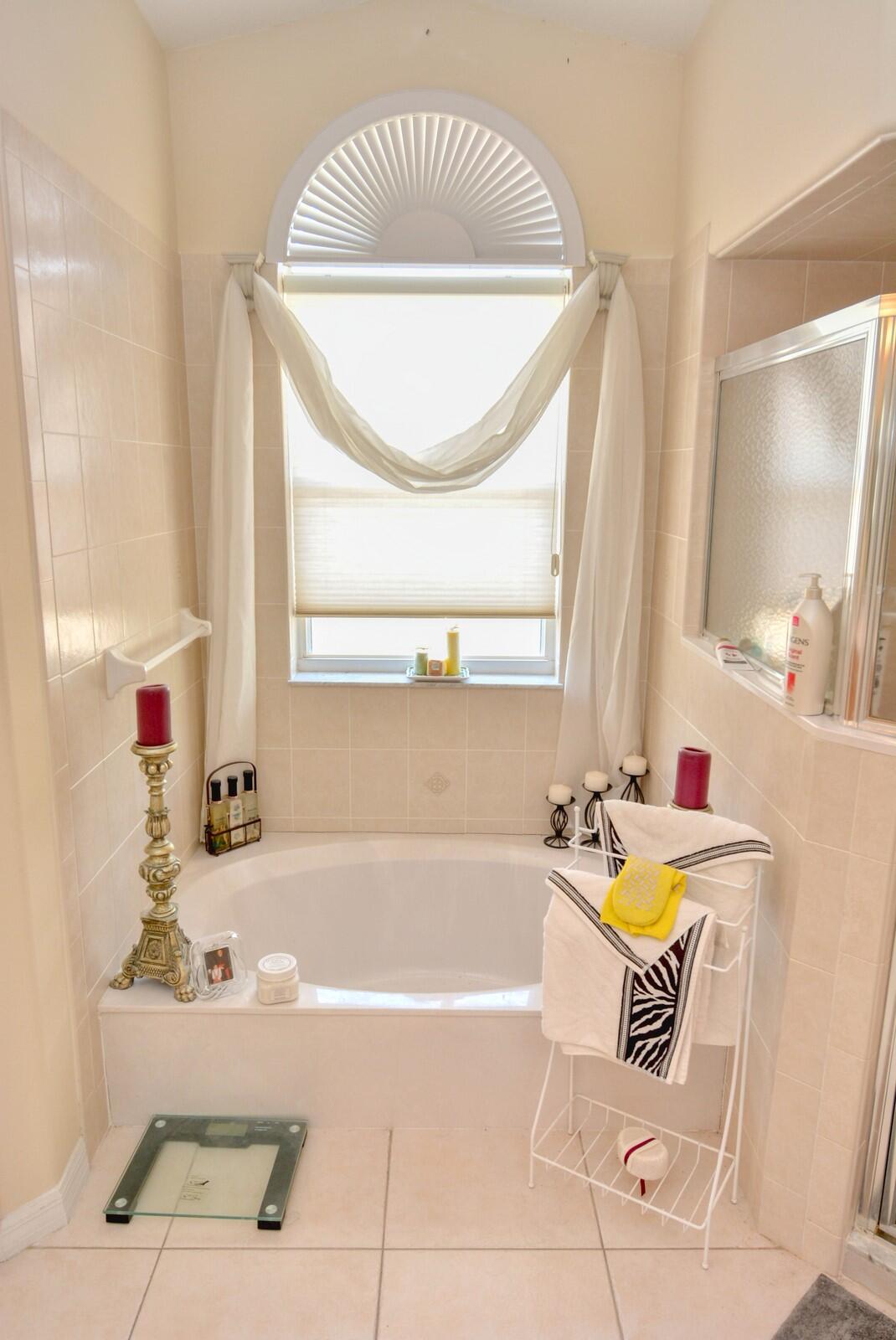 2041 Southwest Villanova Road Port St. Lucie, FL 34953 - Photo 22 of 42 a bath tub sitting next to a white sink and a window