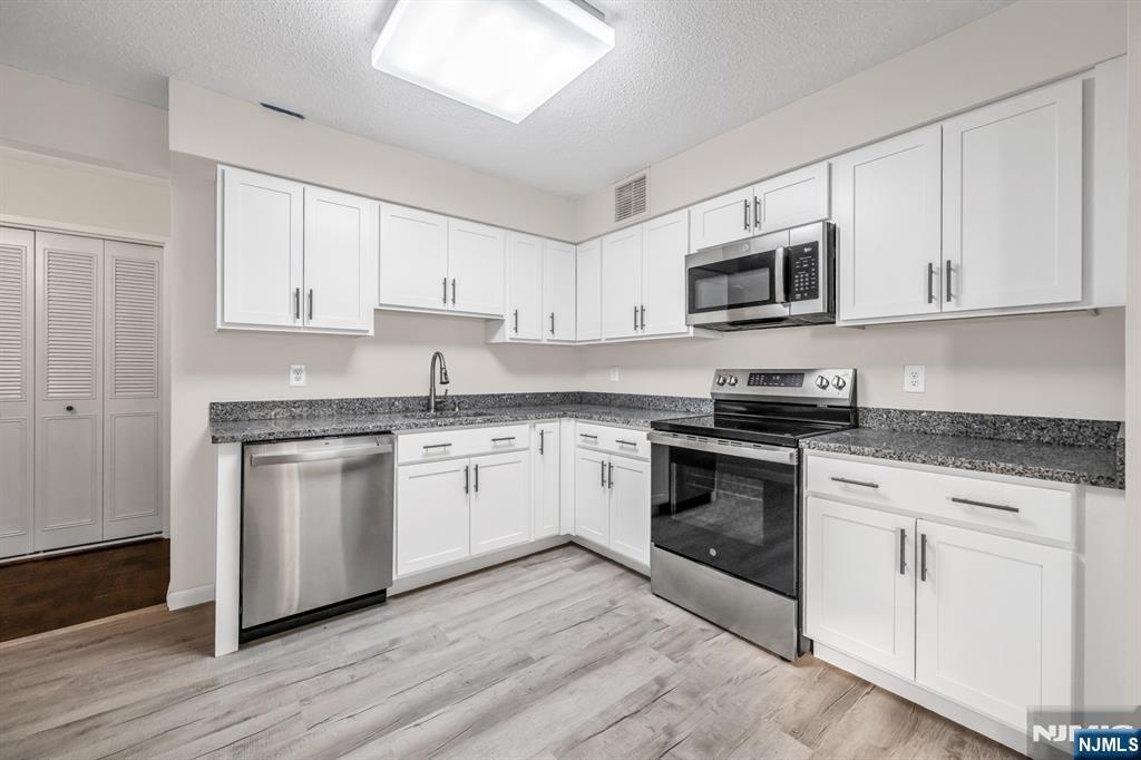 326 Prospect Avenue, Unit 6J Hackensack, NJ 07601 - Photo 3 of 18 a kitchen with granite countertop white cabinets and stainless steel appliances