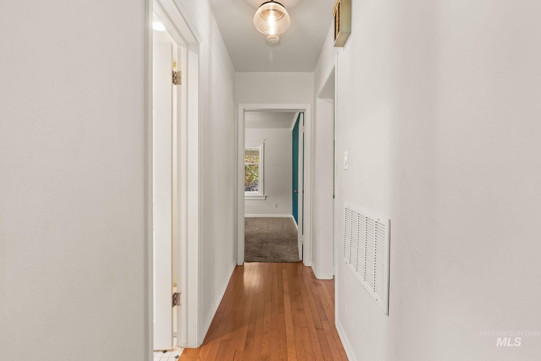 928 3rd Street Clarkston, WA 99403 - Photo 19 of 44 Hallway featuring wood-finish flooring, light-colored walls, a ceiling-mounted light fixture, and a white ventilation grate