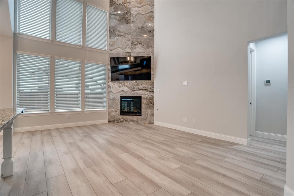2811 Killdeer Trail Prosper, TX 75078 - Photo 2 of 36 Unfurnished living room featuring a high ceiling, a premium fireplace, and light wood finished floors