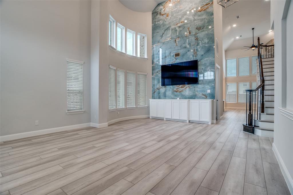 2811 Killdeer Trail Prosper, TX 75078 - Photo 4 of 36 Unfurnished living room featuring a high ceiling, light wood-type flooring, and a ceiling fan