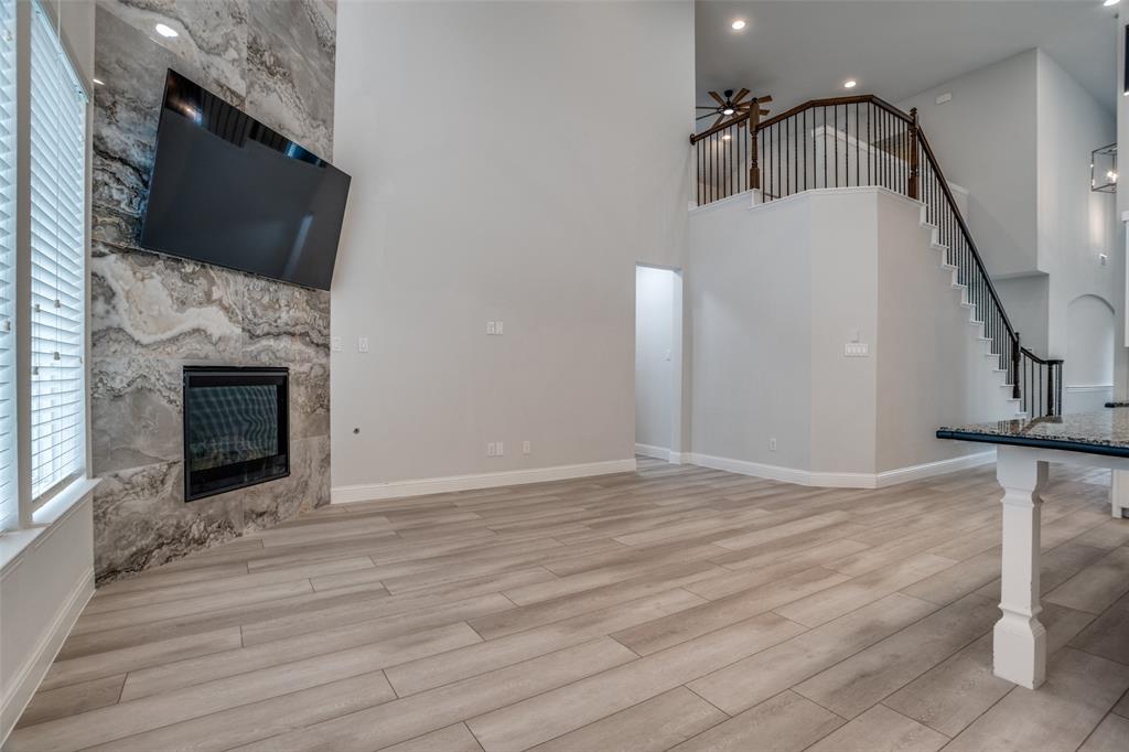 2811 Killdeer Trail Prosper, TX 75078 - Photo 6 of 36 Unfurnished living room featuring a ceiling fan, a glass covered fireplace, light wood-style floors, a high ceiling, and recessed lighting