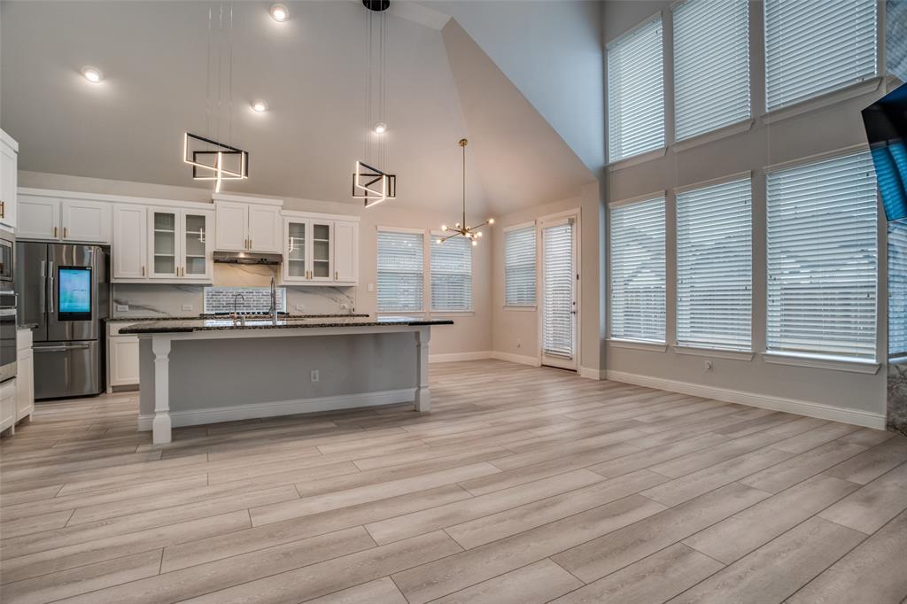 2811 Killdeer Trail Prosper, TX 75078 - Photo 9 of 36 Kitchen with glass insert cabinets, white cabinets, a high ceiling, stainless steel appliances, and decorative backsplash